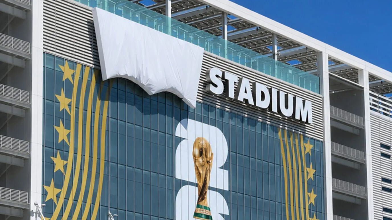 FIFA World Cup 2026 trophy banner draped down a stadium façade with stars and chevrons.