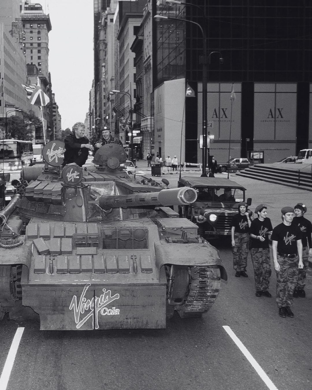 Richard Branson on top of a tank rolling down a New York avenue with Virgin Cola branding and Virgin-uniformed troops marching alongside, launching Virgin Cola in the US.