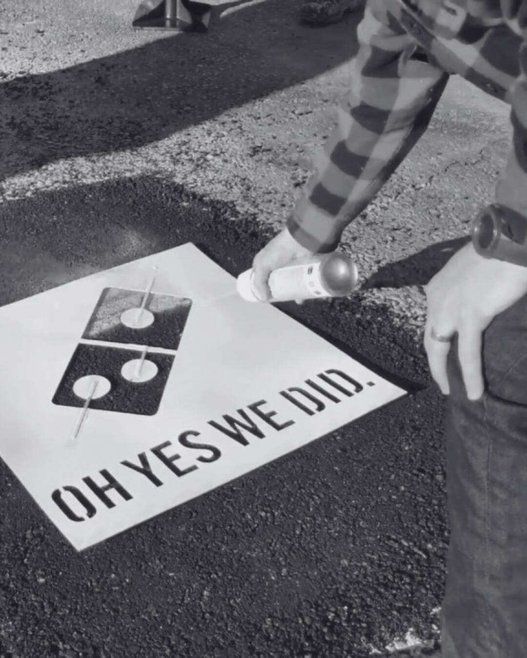 Domino's Paving for Pizza campaign — a worker spray-paints the Domino's logo and the slogan "Oh yes we did." onto a freshly filled pothole.